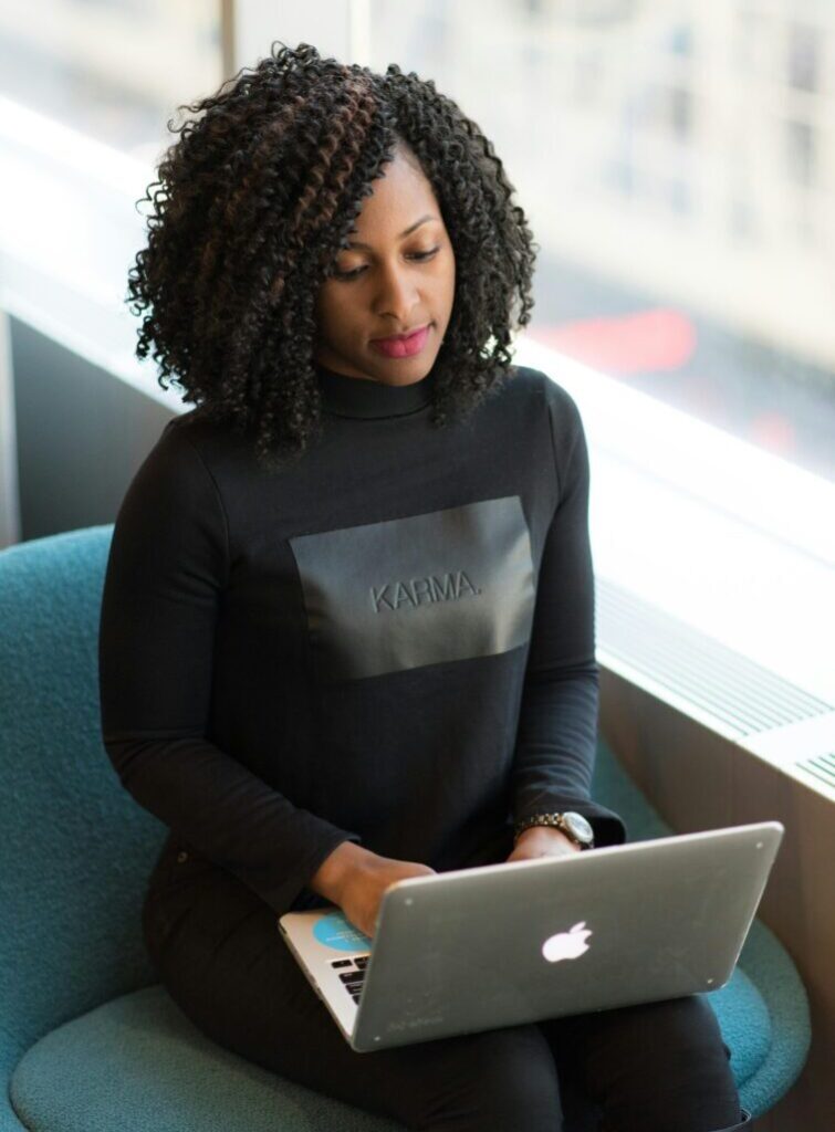 Confident woman using a laptop in a bright office environment, symbolizing modern professional life.